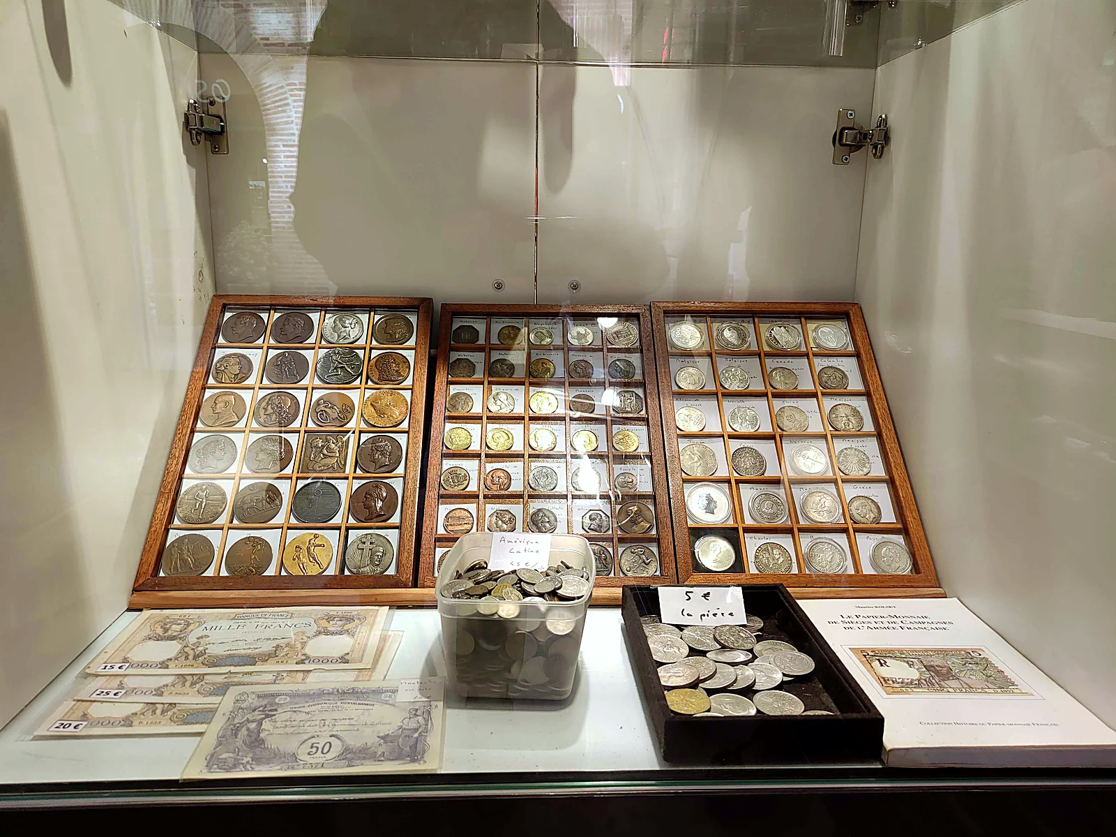 Plateaux de médailles et de monnaies argent, billets Mille Francs et billet de Montauban en vitrine